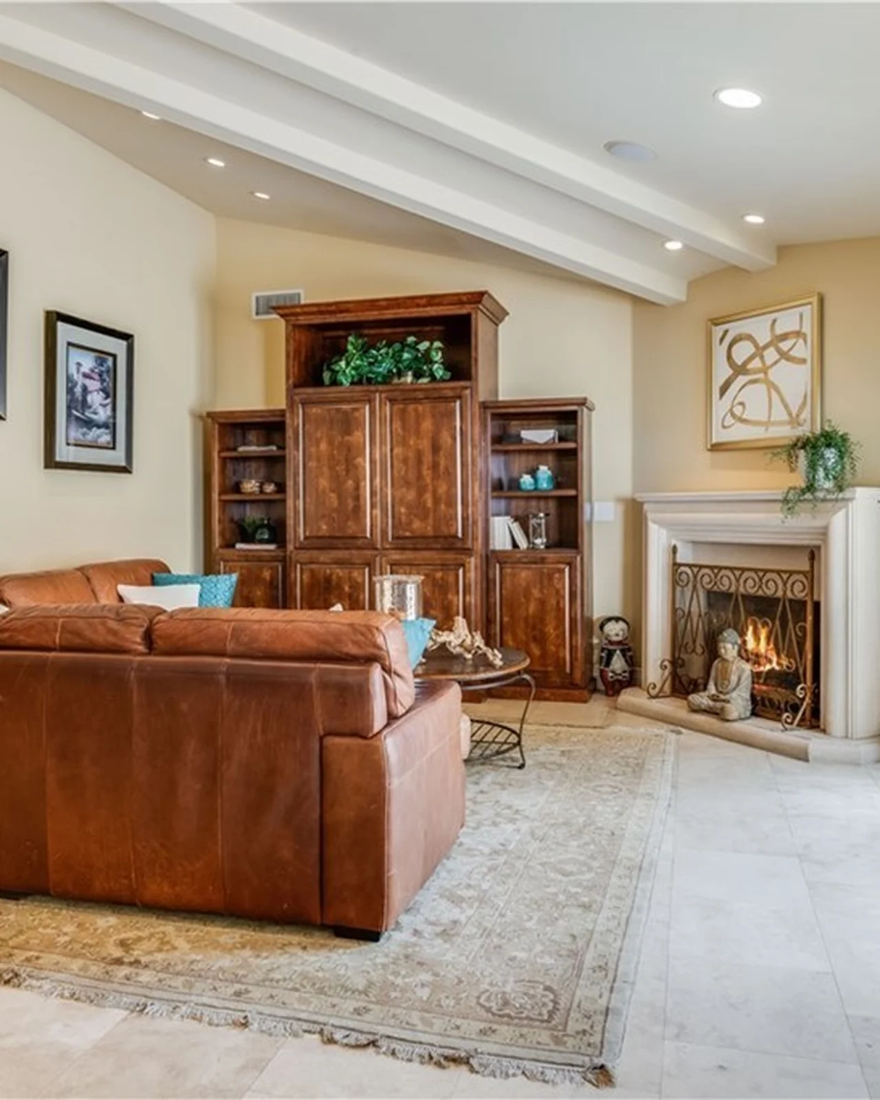 Original family room with brown leather sofas, a stained-wood built-in entertainment cabinet, a traditional stucco fireplace with a carved mantel and a patterned rug
